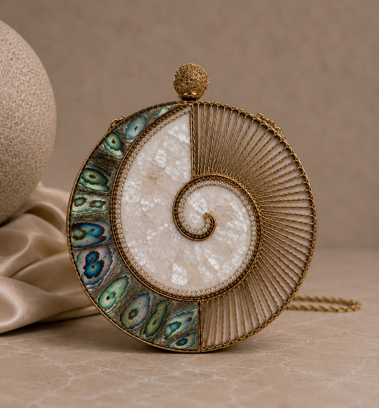 Round clutch with a mother-of-pearl nautilus spiral, gold wire sunburst, crystal trace and abalone crescent